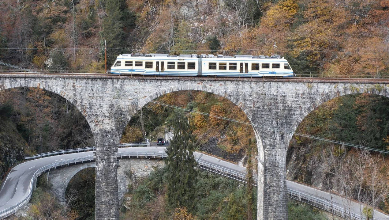 Tren cruzando el puente de Cavallaccio con vistas panorámicas del valle en otoño